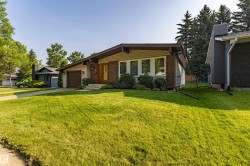 Exterior featuring a brick facade, tan siding, and a prominent front lawn - 