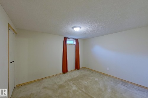 Neutral wall finishes with a ceiling-mounted light fixture and window with red drapery - 16 Brunswick Crescent, St. Albert, AB - Indoor Photo Showing Other Room