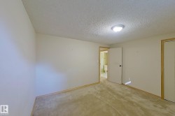 Carpeted interior room with neutral-toned walls, overhead flush-mount lighting, and light wood-finish trim - 