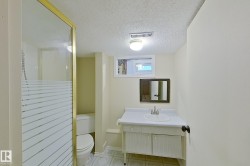 Bathroom featuring a gold-framed shower enclosure with frosted glass, a single vanity with storage, a wall-mounted mirror, and a small window - 