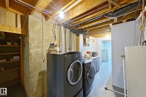 Laundry area featuring a side-by-side washer and dryer, built-in cabinetry with a sink, and exposed ceiling joists - 16 Brunswick Crescent, St. Albert, AB - Indoor Photo Showing Laundry Room