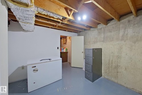 Unfinished basement space with concrete walls, exposed ceiling joists, and painted concrete flooring - 16 Brunswick Crescent, St. Albert, AB - Indoor Photo Showing Basement