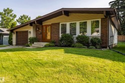 Ranch-style residence featuring a brick and siding facade, a front-facing garage with a paneled door, and a wooden entry door - 