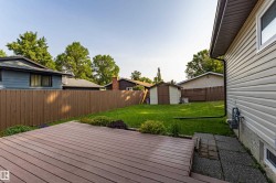 Expansive outdoor living area featuring a spacious composite deck, a large grassy yard, and a storage shed - 