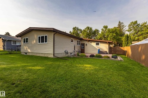 Expansive backyard featuring a manicured lawn, a large paver patio, mature trees, and privacy fencing - 16 Brunswick Crescent, St. Albert, AB - Outdoor