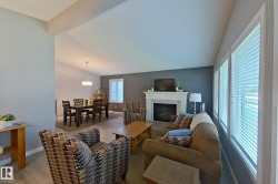 Living area with a fireplace, vaulted ceiling, and wood-finish flooring - 