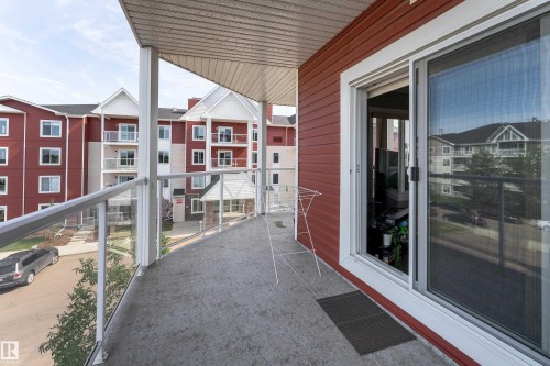 Covered balcony with a concrete surface, glass and metal railing, and an adjacent sliding glass door - #302 2229 44 Av Nw, Edmonton, AB 