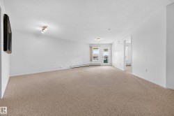 Spacious living area featuring neutral carpet flooring, recessed ceiling lighting, and glass sliding doors with access to a covered balcony - 