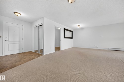 Entry with white paneled door, light-toned tile flooring, and mirrored closet doors - #6430 7331 South Terwillegar Dr Nw, Edmonton, AB 