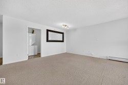 Carpeted interior with white walls, a visible laundry area with stacked appliances, and a ceiling-mounted light fixture - 