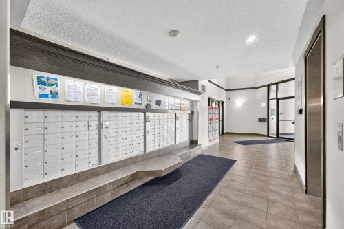 Building entrance featuring floor-to-ceiling glass doors, tile flooring, and integrated mailboxes - #6430 7331 South Terwillegar Dr Nw, Edmonton, AB 