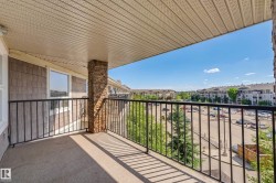 Exterior balcony featuring a stone-clad pillar, black metal railing, and textured siding - 