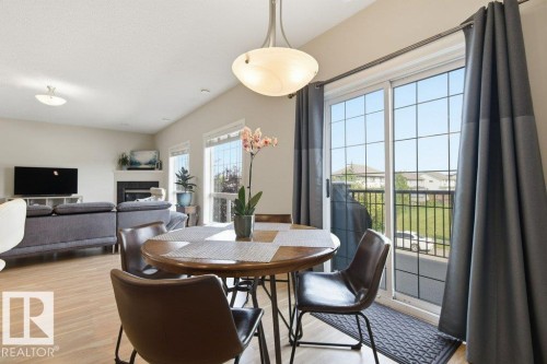 Open-concept living area featuring light wood-finish flooring, vaulted ceilings, and ample natural light from multiple windows - #17 7293 South Terwillegar Dr Nw, Edmonton, AB - Indoor Photo Showing Dining Room