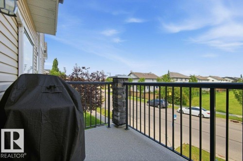Outdoor balcony featuring a stone-clad pillar, black metal railing, and a textured concrete surface - #17 7293 South Terwillegar Dr Nw, Edmonton, AB - Outdoor With Exterior