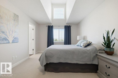 Comfortable bedroom featuring a tall ceiling, upper transom window, and a lower window with privacy blinds - #17 7293 South Terwillegar Dr Nw, Edmonton, AB - Indoor Photo Showing Bedroom