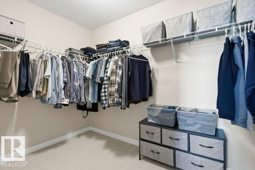 Walk-in closet featuring extensive wire shelving, multiple hanging rods, corner storage, neutral wall color, and carpeted flooring - #17 7293 South Terwillegar Dr Nw, Edmonton, AB - Indoor With Storage