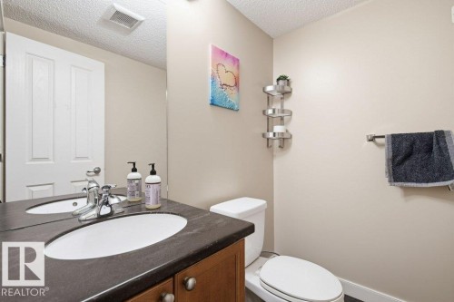 Vanity featuring an integrated oval sink and a dark countertop - #17 7293 South Terwillegar Dr Nw, Edmonton, AB - Indoor Photo Showing Bathroom