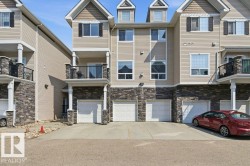 Multi-level townhome featuring beige horizontal siding and stone veneer accents - 