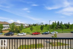 Balcony with black metal railing overlooking a residential street and a verdant hill with mature trees - 