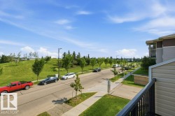 Balcony with black metal railing overlooking a paved street with a concrete sidewalk and green lawn - 