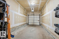 Attached garage with a sectional overhead door, concrete flooring, and bare drywall walls - 