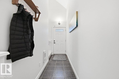 Entryway featuring durable square tile flooring, a white paneled door with upper glass pane, and a wall-mounted light fixture - #17 7293 South Terwillegar Dr Nw, Edmonton, AB - Indoor Photo Showing Other Room