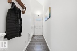 Entryway featuring durable square tile flooring, a white paneled door with upper glass pane, and a wall-mounted light fixture - 
