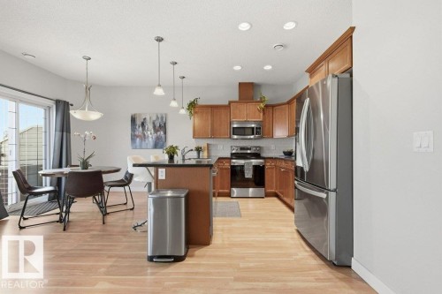 Kitchen featuring wood cabinetry, stainless steel appliances, and wood-finish flooring - #17 7293 South Terwillegar Dr Nw, Edmonton, AB - Indoor Photo Showing Kitchen With Upgraded Kitchen