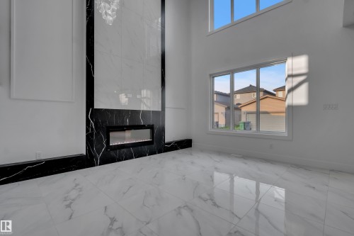 Two-story living area featuring a linear electric fireplace with a black and white marble-style surround - 4005 39 Street, Beaumont, AB - Indoor With Fireplace