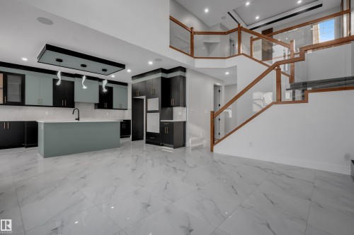 Open-concept interior featuring a modern kitchen with two-tone cabinetry, a central island, and a black faucet - 4005 39 Street, Beaumont, AB - Indoor Photo Showing Other Room