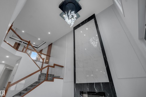 Grand entryway featuring a contemporary staircase with wood-finish handrails and glass panels - 4005 39 Street, Beaumont, AB - Indoor Photo Showing Other Room