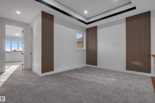 Spacious room featuring modern wall paneling, a tray ceiling with black trim, recessed lighting, and soft grey carpeting - 4005 39 Street, Beaumont, AB - Indoor Photo Showing Other Room