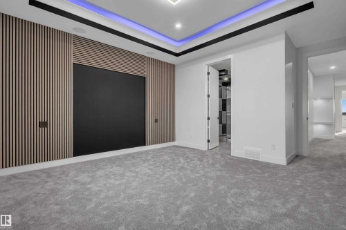 Recessed lighting in a tray ceiling with accent lighting, wall-mounted speakers, and a wood-slat feature wall - 4005 39 Street, Beaumont, AB - Indoor Photo Showing Other Room
