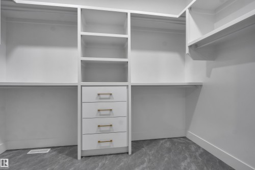 Custom white built-in closet system featuring multiple shelving units, hanging rods, and a four-drawer dresser with gold-tone hardware - 4005 39 Street, Beaumont, AB - Indoor With Storage