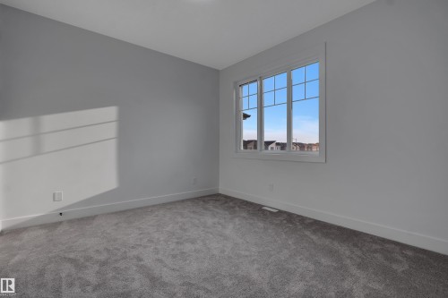 Bright room featuring a multi-pane window, neutral gray walls, and plush gray carpeting - 4005 39 Street, Beaumont, AB - Indoor Photo Showing Other Room