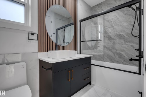 Contemporary bathroom featuring a dark vanity with a white countertop and vessel sink - 4005 39 Street, Beaumont, AB - Indoor Photo Showing Bathroom