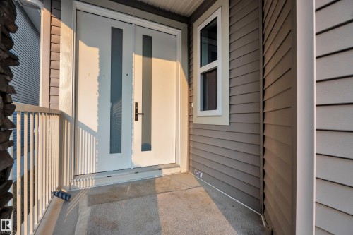 Entry featuring a white door with frosted glass inserts, a white framed window, and brown horizontal siding - 4005 39 Street, Beaumont, AB - Outdoor With Exterior