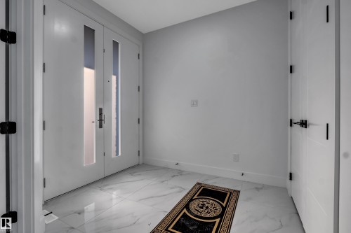 Entryway featuring a double door with vertical frosted glass inserts and dark hardware, set against light gray walls with white baseboards - 4005 39 Street, Beaumont, AB - Indoor Photo Showing Other Room