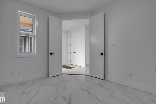 Spacious room featuring large format tile flooring, a window with white trim, and a pair of modern doors with dark hardware - 4005 39 Street, Beaumont, AB - Indoor Photo Showing Other Room