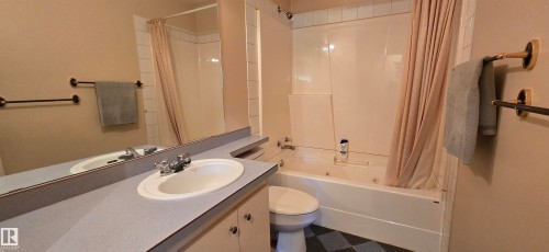Spa-inspired bathroom featuring a ceramic pedestal sink with chrome faucet, quartz countertop, and ample mirror lighting - 5706 52 Street, Vegreville, AB 