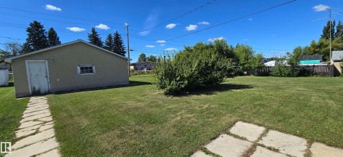 Detached garage with a side entry door, exterior window, and concrete paver pathway - 5706 52 Street, Vegreville, AB 