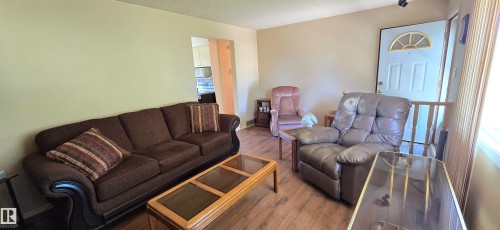 Wood-finish flooring throughout the living area, neutral wall tones, and a white entry door with an arched transom window - 5706 52 Street, Vegreville, AB 