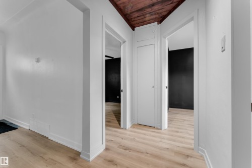 Wood-finish flooring with white baseboards, white walls, and a wood-paneled ceiling - 12116 81 Street Nw, Edmonton, AB 