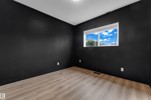 Neutral-toned wood-finish flooring, a contemporary window with white blinds, and dark accent walls with contrasting trim - 12116 81 Street Nw, Edmonton, AB 