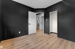Wood-finish flooring, dark wall finishes, a white interior door, and an open closet - 