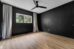 Wood-finish flooring, white window frame, and a black ceiling fan - 