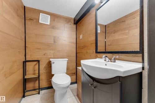 Wood-finish wall paneling, white pedestal toilet, and vanity with integrated basin - 12116 81 Street Nw, Edmonton, AB 