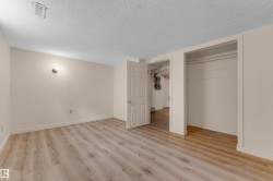 Wood-finish flooring, neutral wall paint, built-in closet with hanging rod, and ceiling-mounted light fixture - 