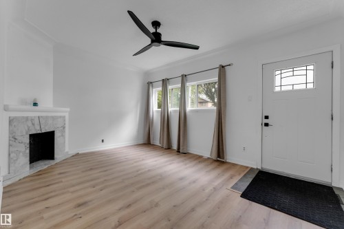 Light wood-finish flooring, white walls, and a decorative fireplace - 12116 81 Street Nw, Edmonton, AB 
