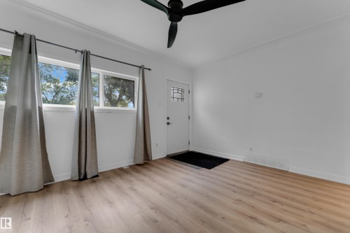 Wood-finish flooring, two large windows, a ceiling fan, and a front entry door with decorative glass - 12116 81 Street Nw, Edmonton, AB 